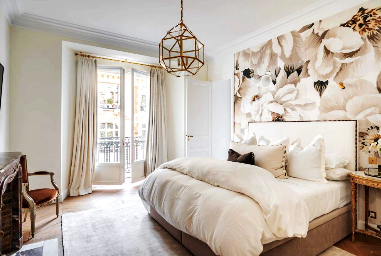 Rue Danton Paris fractional ownership Bright bedroom with a large bed, floral wallpaper, and French doors to a balcony.